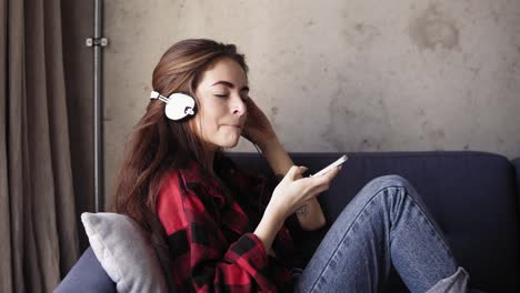 Una-Joven-Atractiva-Con-Auriculares-En-La-Cabeza-Disfruta-Escuchando-Su-Música-Favorita.