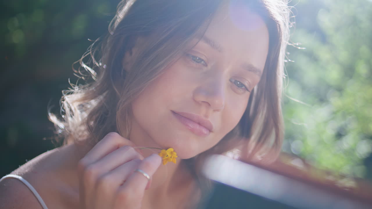 Romantic woman reading book at sunshine park closeup. Gentle lady holding flower