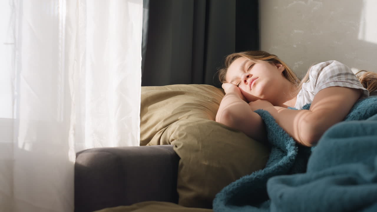 Woman Resting Peacefully Under Teal Blanket, Calm Lady Enjoying Tranquil Moments On Comfy Furniture, Serene Woman Lost In Gentle Thoughts While Lounging Beneath Soothing Teal Covering