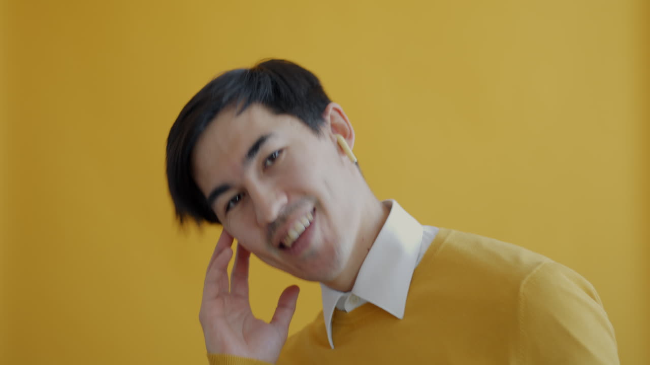Man in a yellow sweater smiling against a yellow background