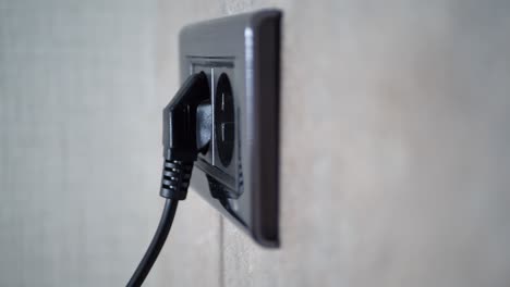 close-up of a black electrical outlet with a plug inserted