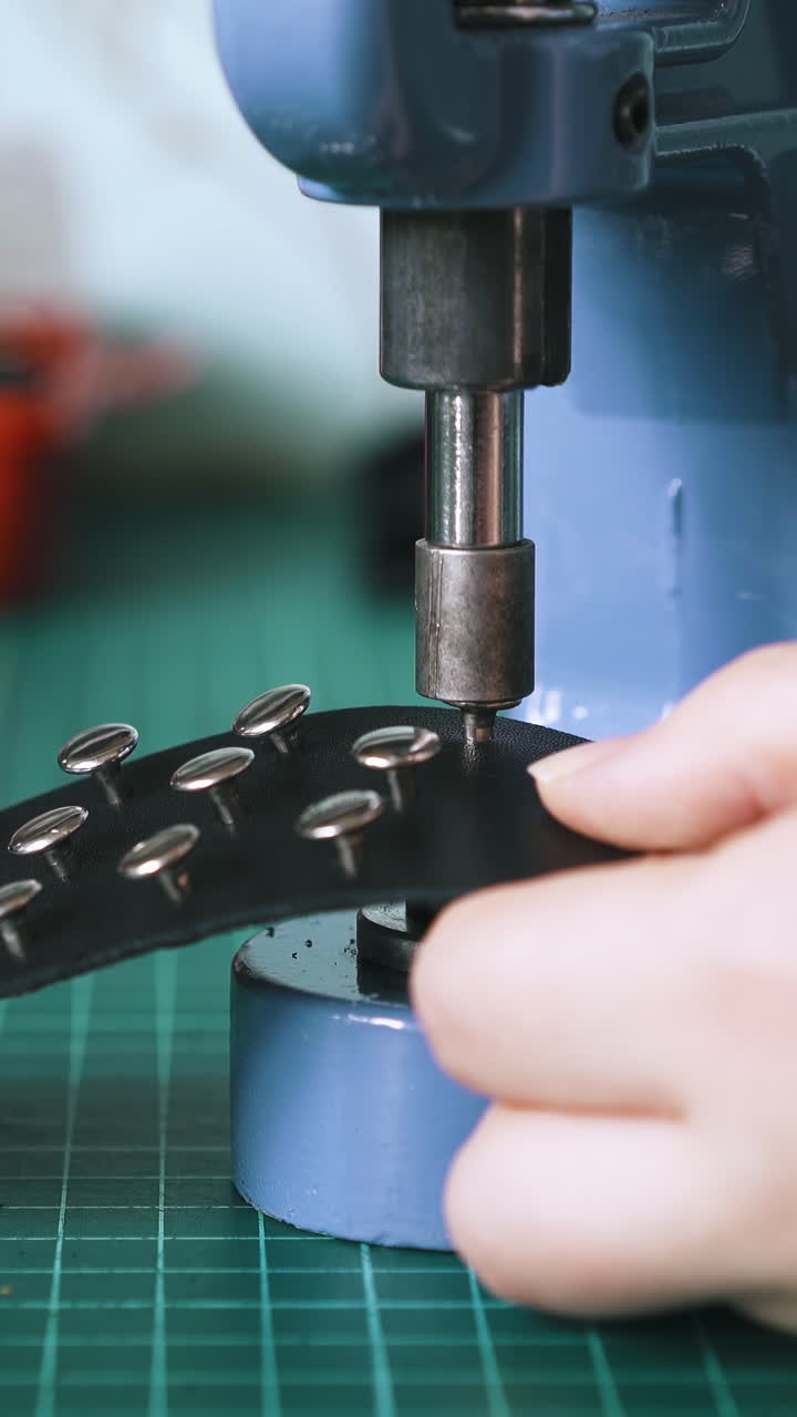 CU: Professional tailor fixes silver holnitens on black leather choker with special press machine close view