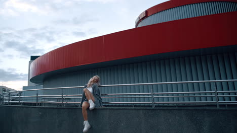 young female model urban fashion posing on modern building in city.