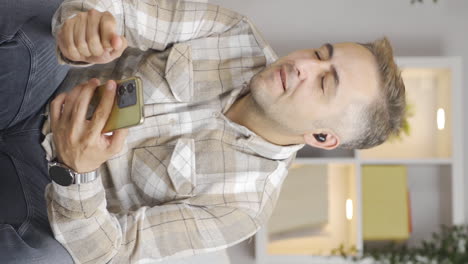 Vertical-video-of-Happy-man-listening-to-music-with-headphones.