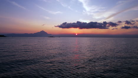 Sunrise-Above-Aegean-Sea-and-Greek-Island-Coastline,-Flying-Low-Above-Water,-Drone-Shot