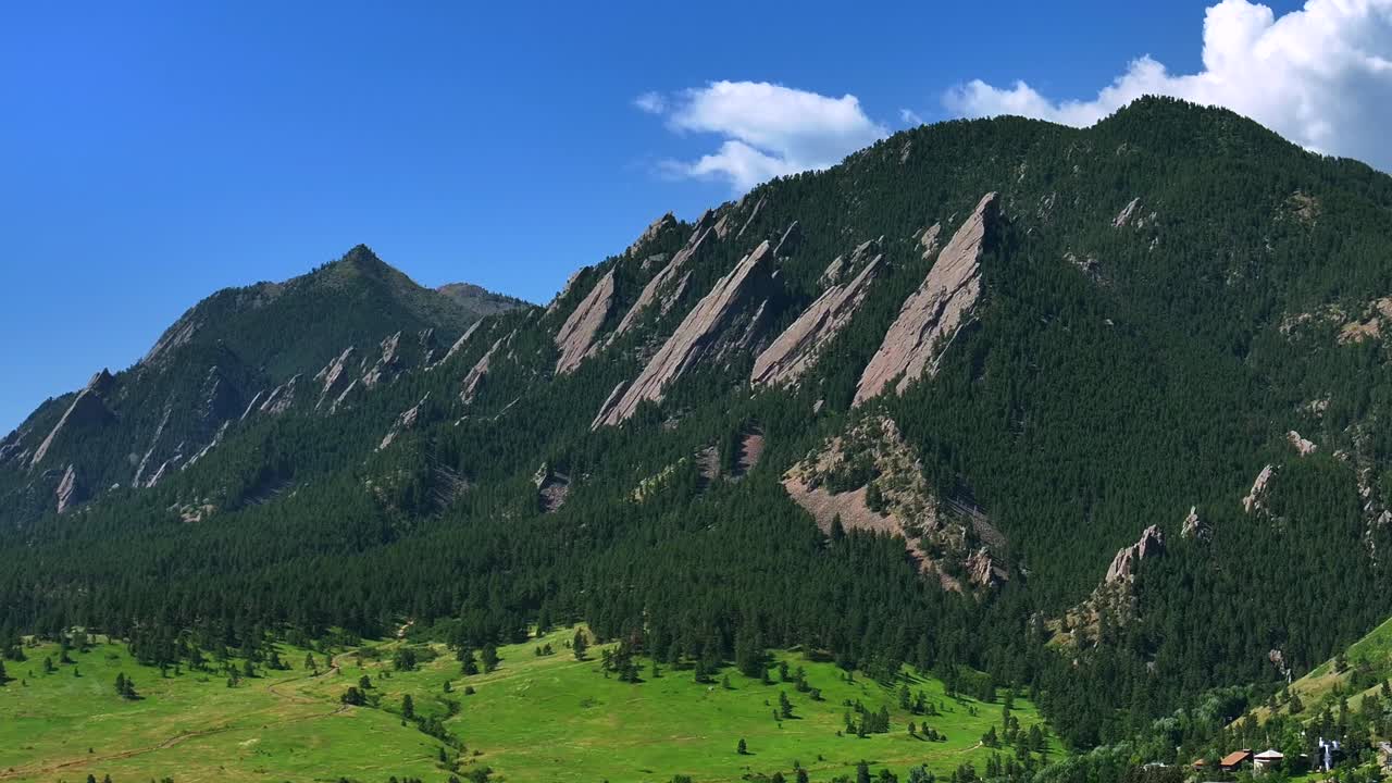 Boulder Colorado Flatirons slanted Front Range Rocky Mountains aerial drone Chautauqua Park Boulder Creek Canyon Shanahan Ridge Mountain Park hiking trail summer blue sky forward pan up motion