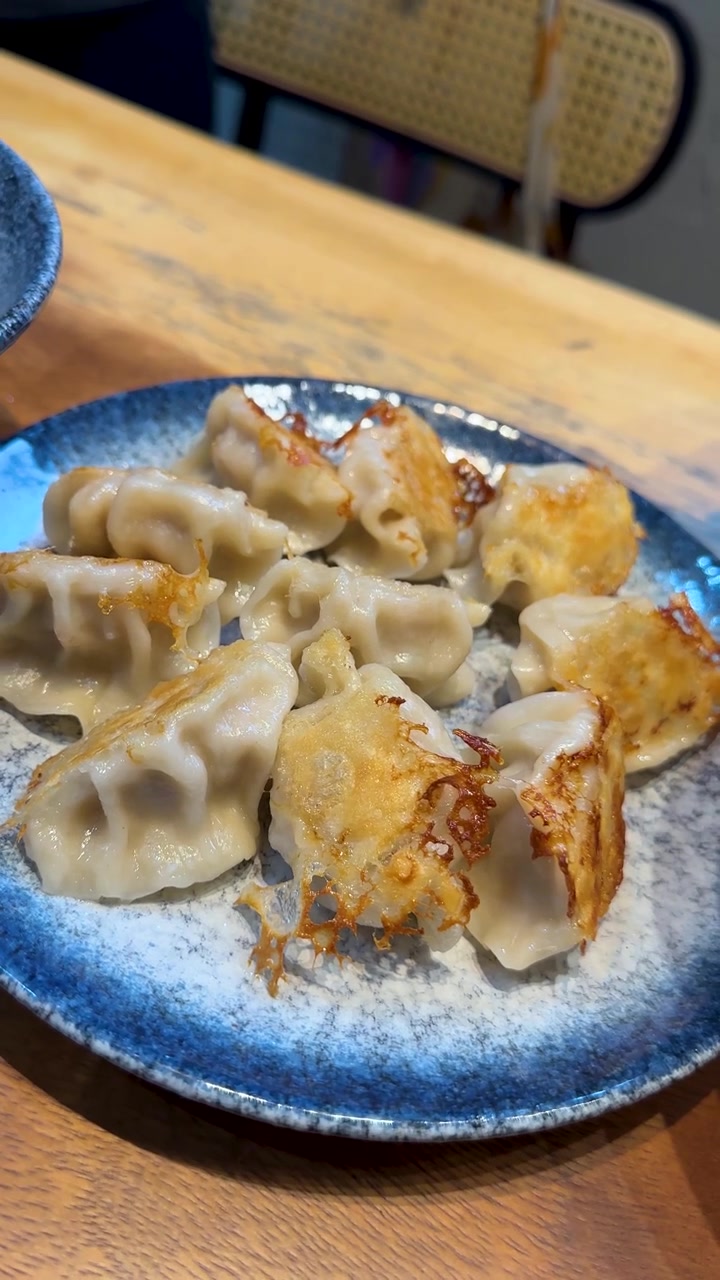 Close-up of crispy golden-brown dumplings on a blue plate in a Taiwanese restaurant setting.