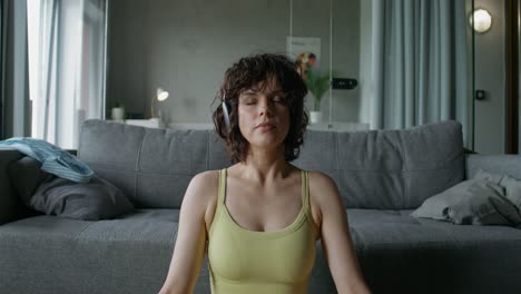 mujer meditando en casa mientras escucha música