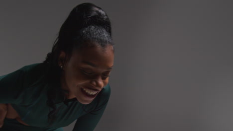 close up studio shot of female athlete wearing tracksuit training out of breath and recovering after exercise