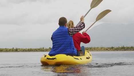 caucasian couple having a good time on a trip to the mountains, kayaking together on a lake