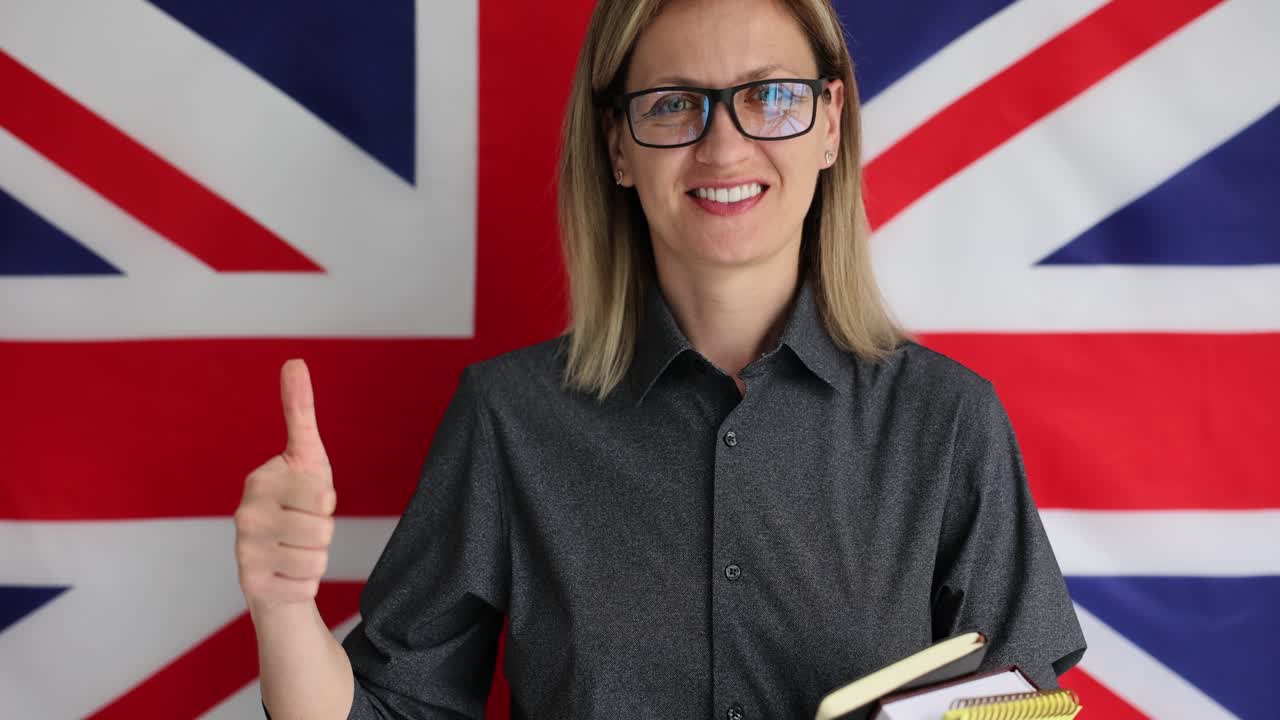 Woman smiling and giving a thumbs up in front of a British flag, suggesting English language proficiency or education