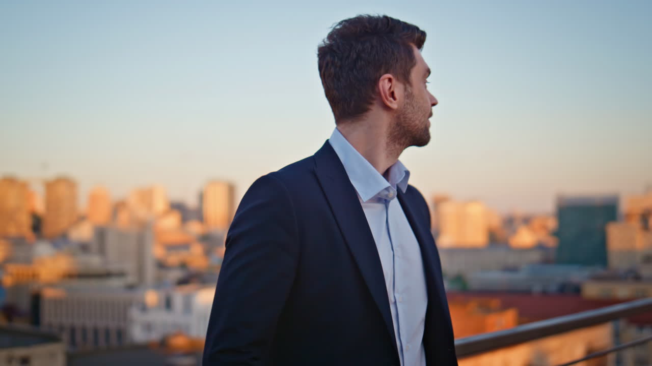 Successful man overlooking urban skyline on rooftop sunset closeup. Man leader