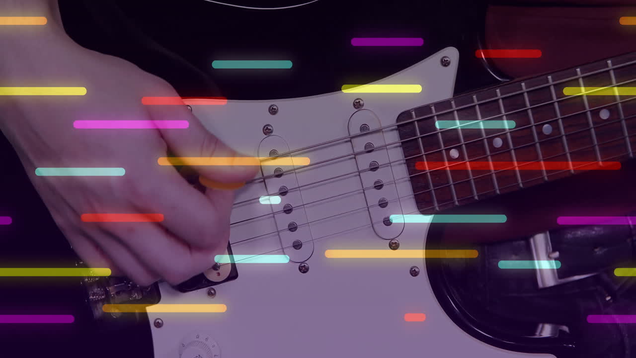 Male guitarist holding pick and strumming electric guitar in music studio with light streaks