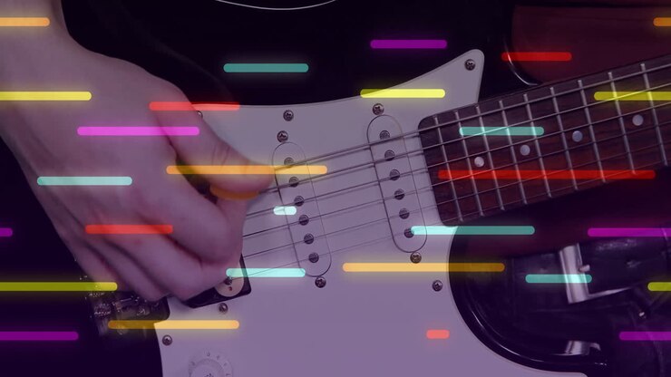 Male guitarist holding pick and strumming electric guitar in music studio with light streaks