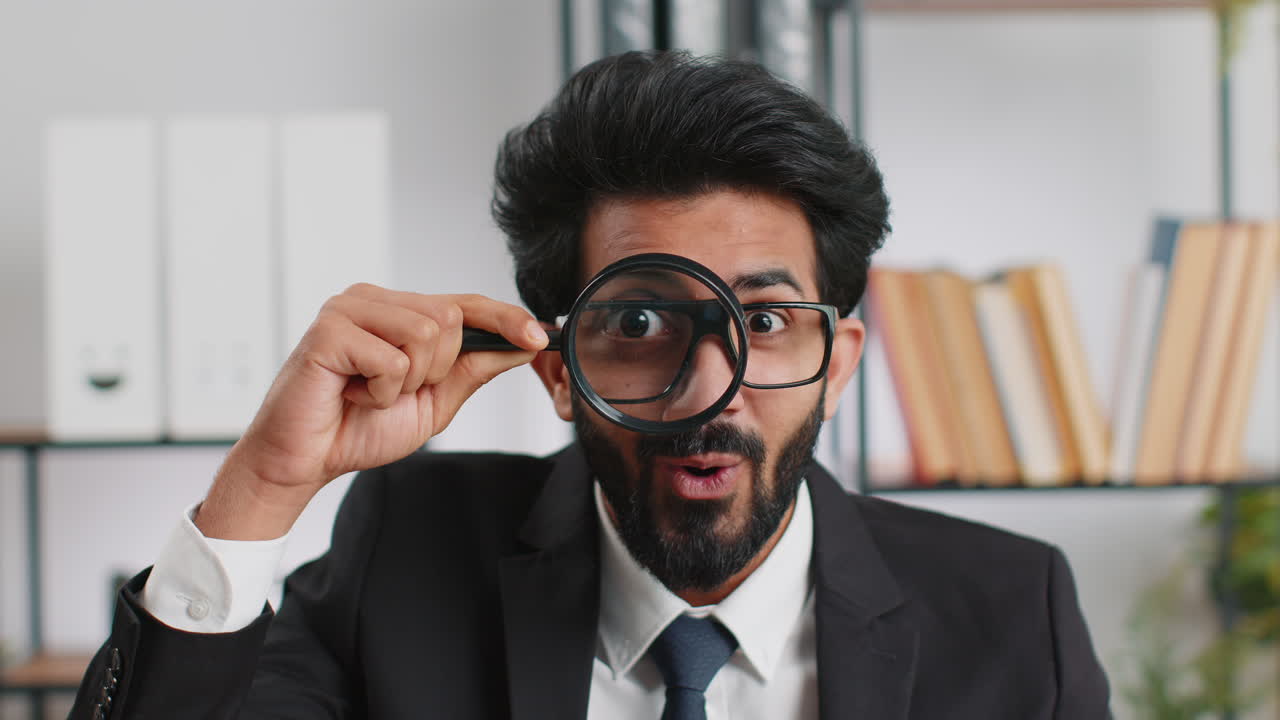 Business man holding magnifying glass near face looking with big zoomed eye searching analysing