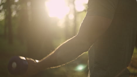 man exercising with dumbbell in forest