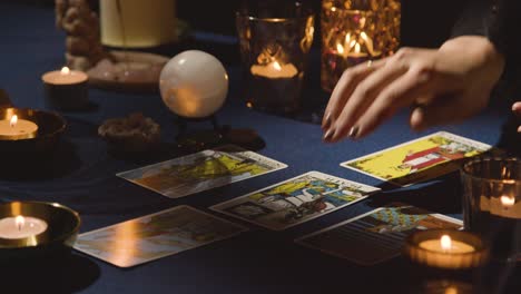 primer plano de una mujer dando una lectura de cartas del tarot en una mesa a la luz de las velas sosteniendo la carta de la muerte 2