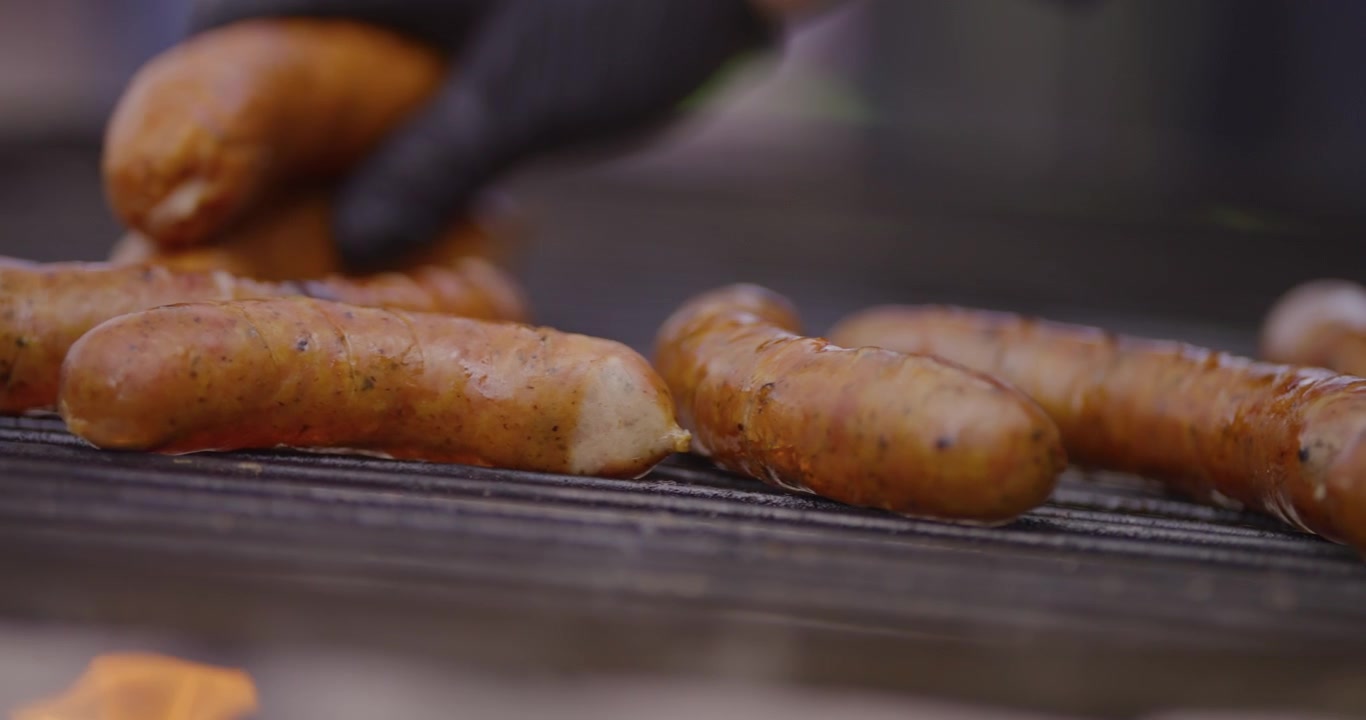 Primo piano di salsicce che sfrigolano su una griglia calda per barbecue