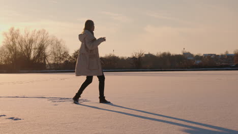 woman dancing on a frozen lake at sunset