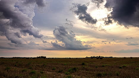 Dark-storm-clouds-form-over-a-pasture-with-straw-bales-ready-to-be-transported