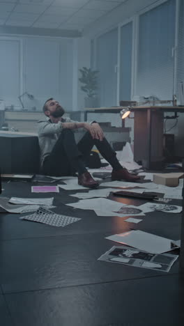 stressed employee sitting on the floor in a messy office