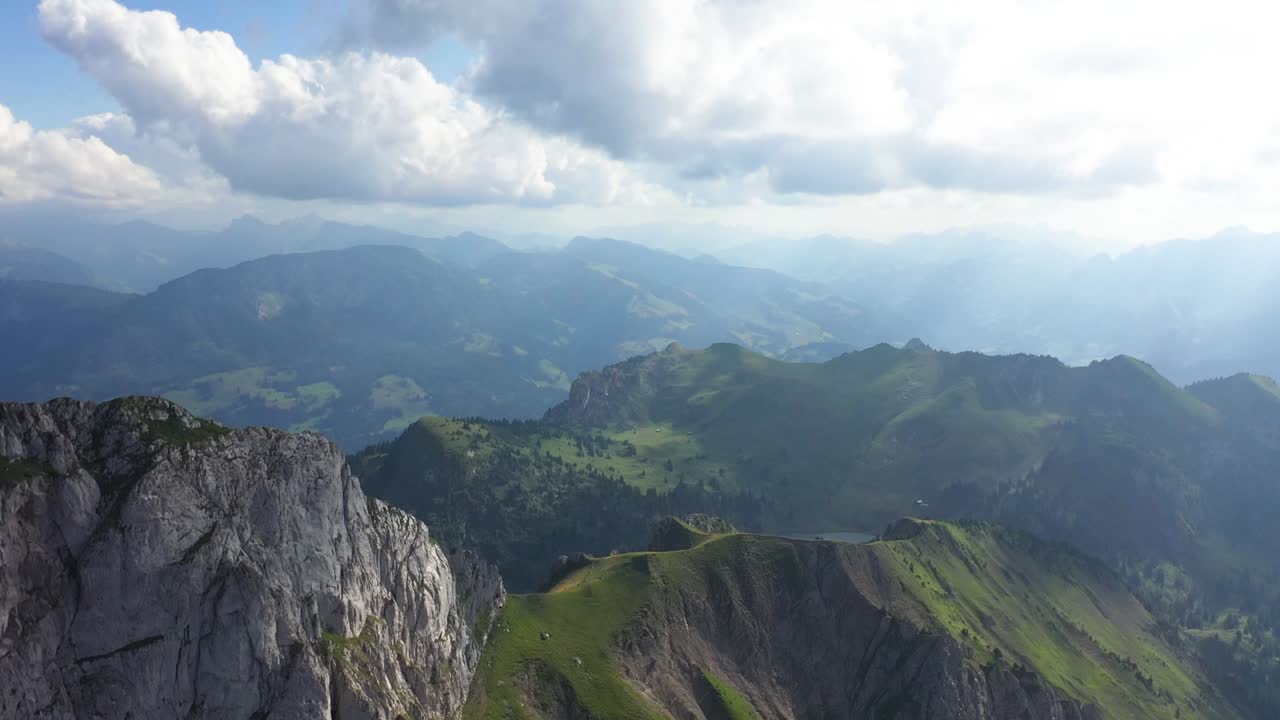 tiro de drones bajando y al lado de stockhorn, suiza con nubes blancas dramáticas y rayos de sol que atraviesan, dando magia y color al vasto y majestuoso paisaje en un día caluroso y soleado