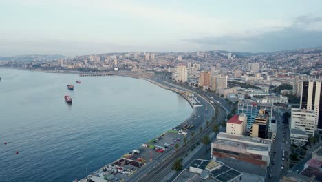 Dolly-Aéreo-En-Edificios-De-La-Ladera-De-La-Ciudad-De-Valparaíso-Y-Barcos-Navegando-Cerca-De-La-Costa-En-Un-Día-Nublado,-Chile