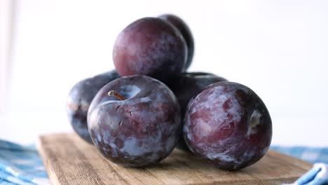 pile of fresh plums on a wooden cutting board