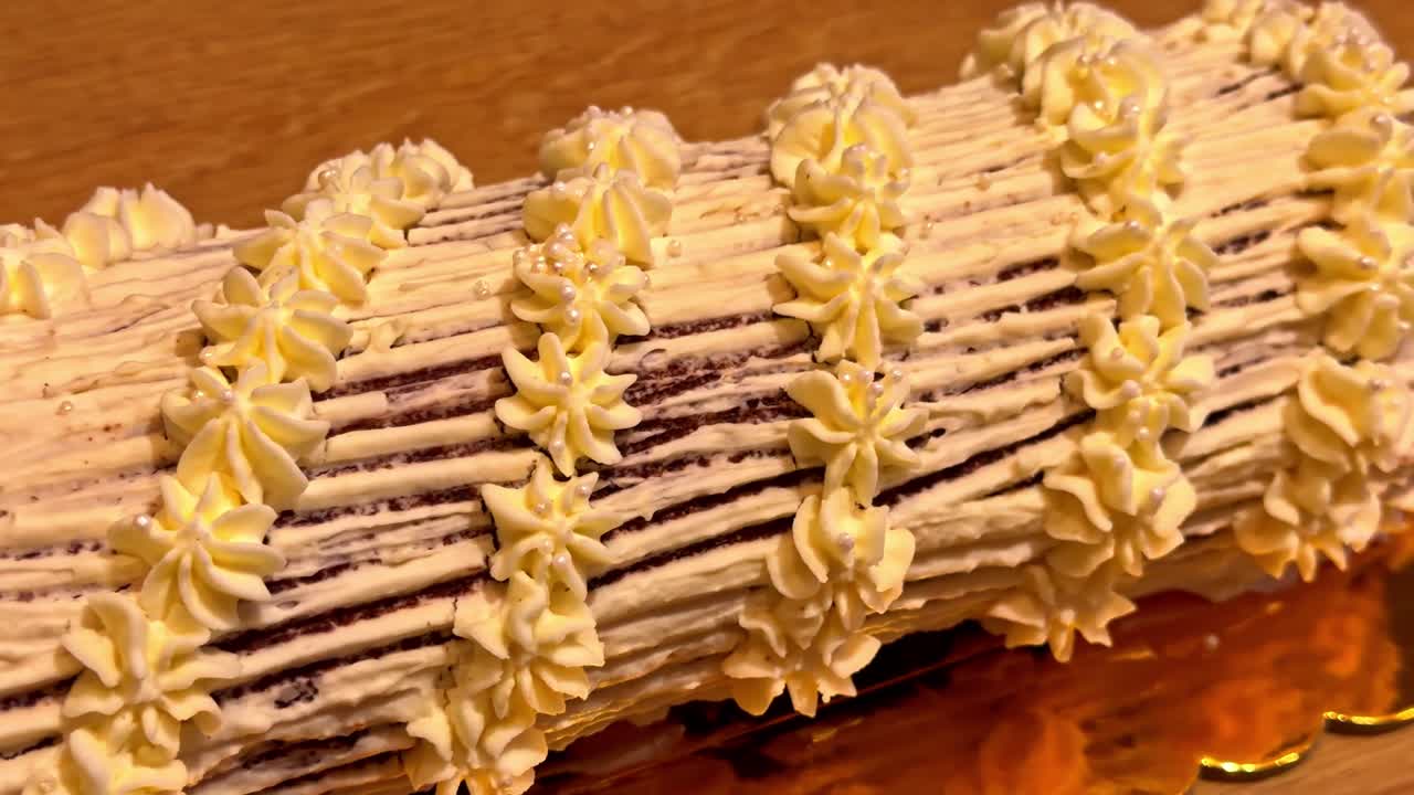 Tronchetto di Natale decorato con spirali di crema su tagliere di legno, dolce festivo