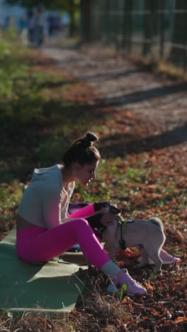 mujer haciendo ejercicio con su pug en un parque en otoño