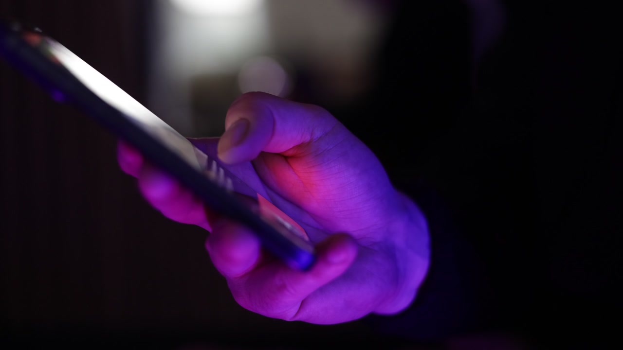 Riprese ravvicinate di una persona che tiene uno smartphone e scorre i contenuti su un dispositivo mobile.