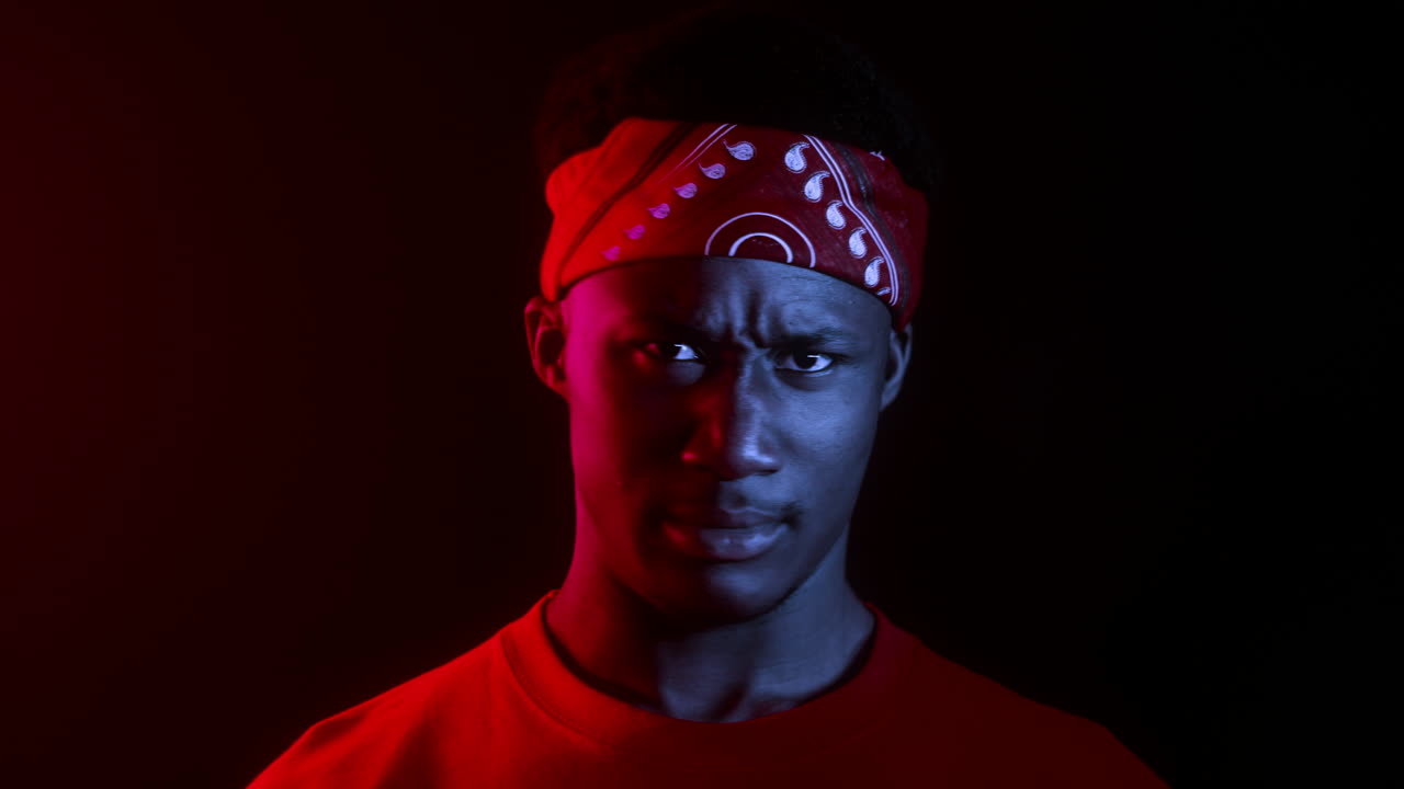 hombre con iluminación roja y azul con bandana