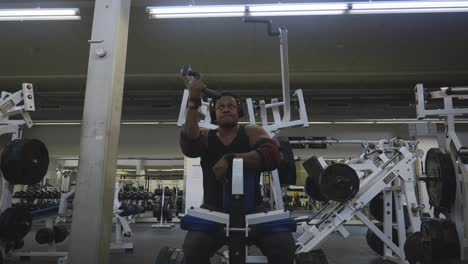 black male bodybuilder strongman athlete is lifting black weights with right hand on sports equipment in 4k