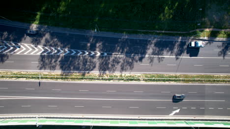 Draufsicht-Auf-Fahrzeuge-Auf-Einer-Sonnenbeschienenen-Straße-Mit-Baumschatten-Und-Fußgängerüberwegen