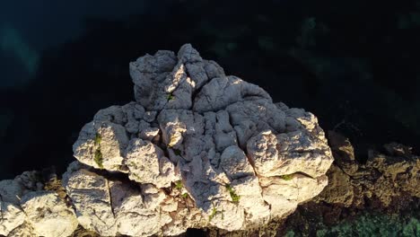 Breathtaking-top-down-aerial-view-of-offshore-white-rock-formation-surround-by-crystal-clear-turquoise-water,-orbit,-rising-day