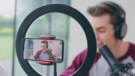 vlogger masculino o influencer podcast de transmisión en vivo en casa grabado en un teléfono móvil