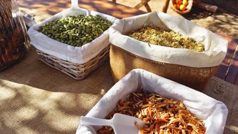 small baskets and jars with various spices on wooden table