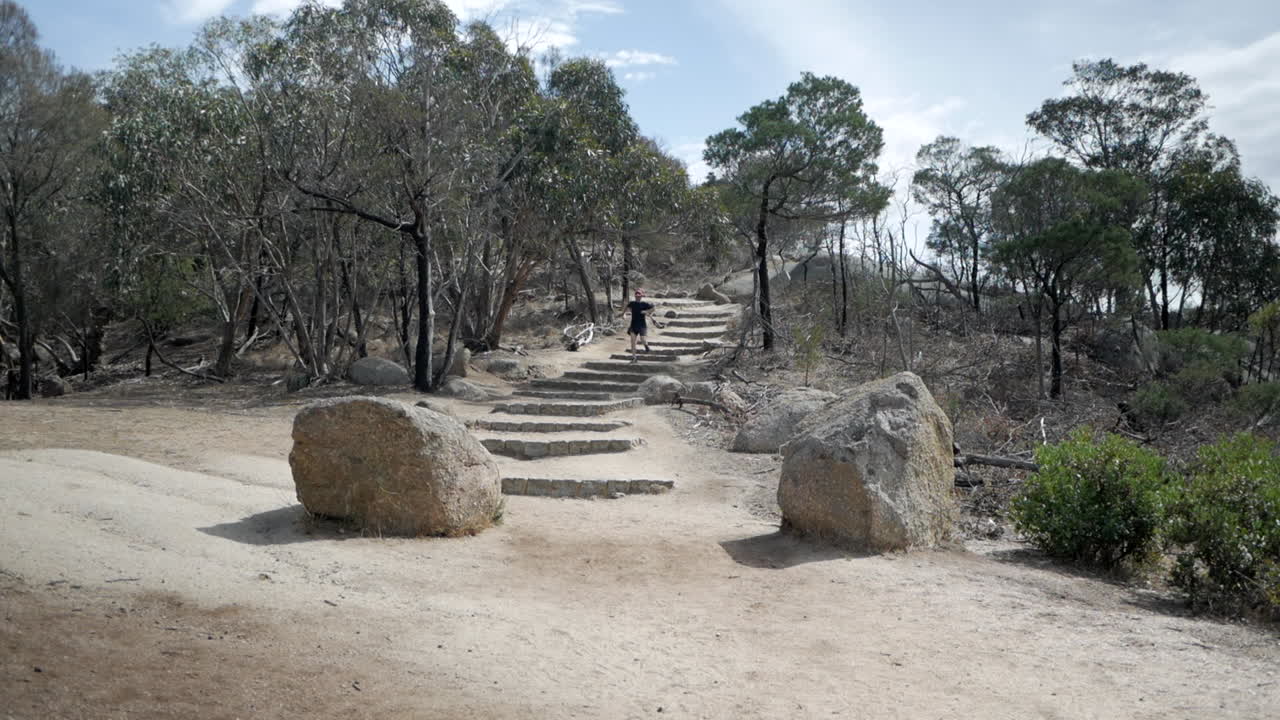 hombre corriendo desde la cumbre, pico flinders, parque nacional you yangs, victoria australia
