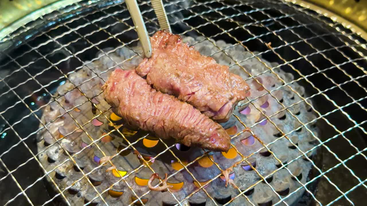 Nærbilde av råe biffstrimler som steker over åpen flamme på en tradisjonell kullgrill