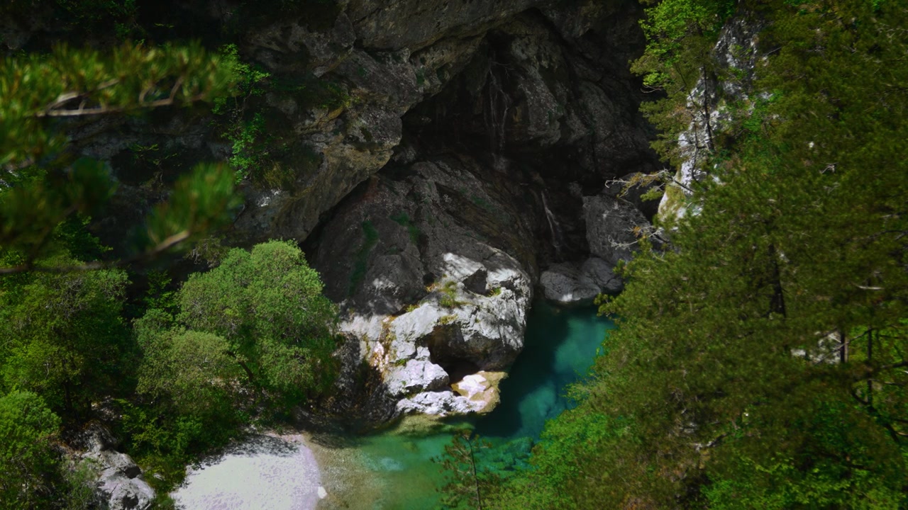 Cascata d'acqua limpida che si getta in una piscina montana incontaminata color turchese alle Pozze Smeraldine nelle Dolomiti
