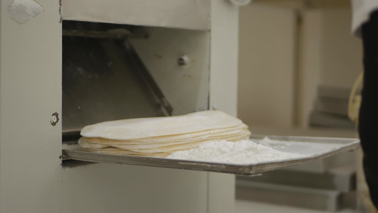 the baker's hands in gloves fold the blanks of dough cakes, rolled by a special machine. Production of the national flatbread lavash. Close-up.
