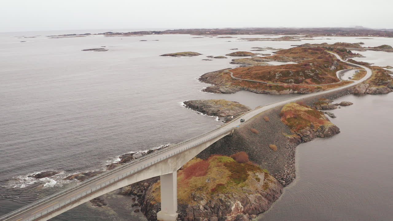 автомобиль пересекает знаменитый мост сторсейсунд на дороге через атлантический океан в пасмурный день, норвегия
