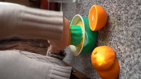 vertical shot of a woman squeezing fresh orange fruit juice