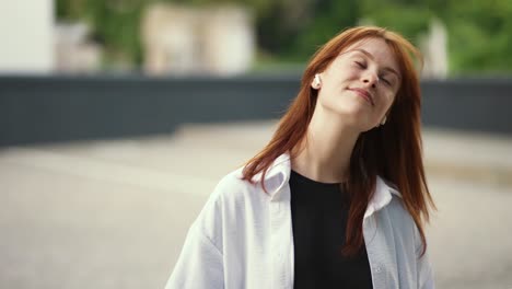 una chica pelirroja con auriculares escucha música y baila.