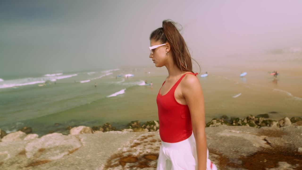Young Woman Walking Along Rocky Beach Shoreline