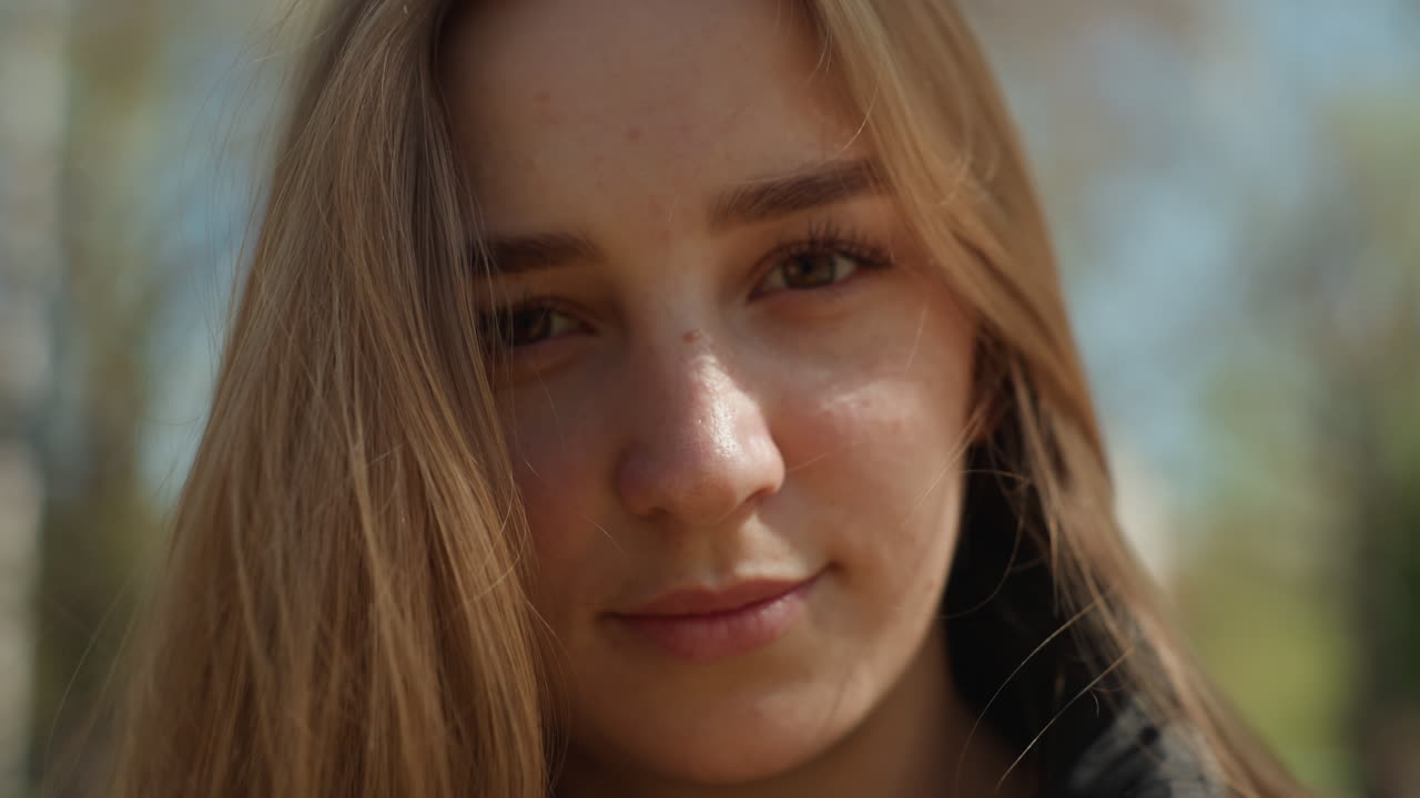 Una mujer de ojos brillantes irradia una tierna serenidad al aire libre; una joven sujeta suavemente un ramo de flores con una sonrisa radiante; una hermosa joven mira suavemente con flores en un ambiente cálido de luz solar natural.