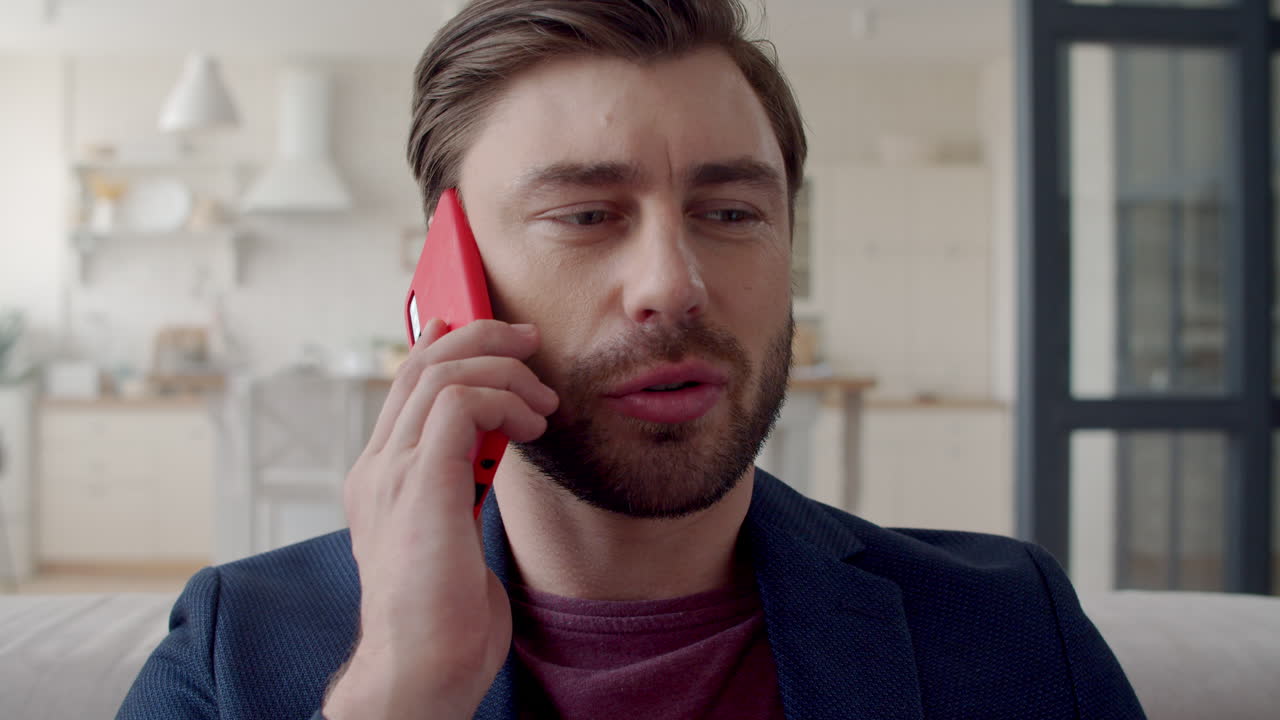 Young business man feeling doubt at remote office. Guy talking on smartphone.