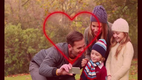 animation of neon heart over happy caucasian family taking selfie outdoors