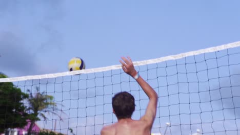 volleyball being smacked over net by caucasian male filmed from backside in slow motion