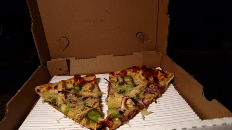 slow moving motion shot, of two slices of pizza in cardboard box, leftovers for a snack